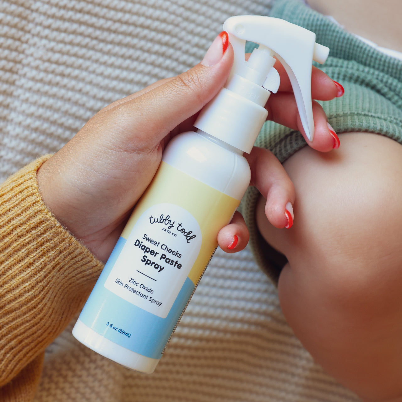 Hand holding Sweet Cheeks Diaper Paste Spray